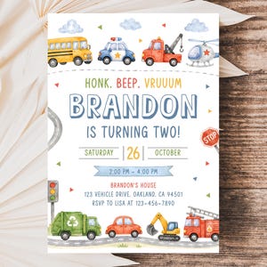 May include: A birthday invitation card featuring watercolor illustrations of a yellow school bus, police car, tow truck, helicopter, garbage truck, car, excavator, and fire truck. Text reads: HONK. BEEP. VRUUUM BRANDON IS TURNING TWO! SATURDAY 26 OCTOBER.