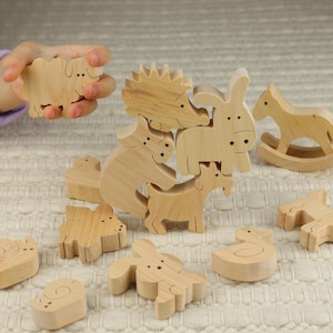 Può includere: Un set di giocattoli di legno impilabili a forma di animali. Il set include un maiale, una pecora, un asino, una capra, un riccio, un cavallo, un'anatra e un coniglio. I giocattoli sono tutti in legno naturale e non sono dipinti.