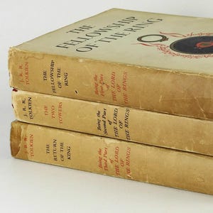 Puede incluir: Un conjunto de tres libros de tapa dura, La Comunidad del Anillo, Las Dos Torres y El Retorno del Rey, de J.R.R. Tolkien. Los libros est&aacute;n apilados uno encima del otro, con el primer libro en la parte superior y el &uacute;ltimo libro en la parte inferior.
