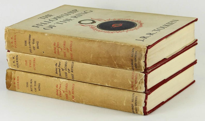 Puede incluir: Un conjunto de tres libros de tapa dura, La Comunidad del Anillo, Las Dos Torres y El Retorno del Rey, de J.R.R. Tolkien. Los libros est&aacute;n apilados uno encima del otro, con el primer libro en la parte superior y el &uacute;ltimo libro en la parte inferior.