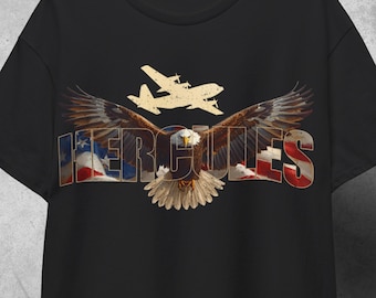 Puede incluir: Camiseta negra con un diseño gráfico de un águila con las alas extendidas, la palabra "HERCULES" en colores patrióticos y una silueta de avión. El diseño incorpora elementos de la bandera estadounidense.