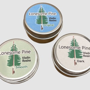 May include: Three round tins of Lonesome Pine violin rosin. Each tin has a silver lid and a label with a green pine tree illustration and the words "Lonesome Pine Violin Rosins." The labels are light blue, light green, and off-white, with the words "Original," "Smooth," and "Dark."
