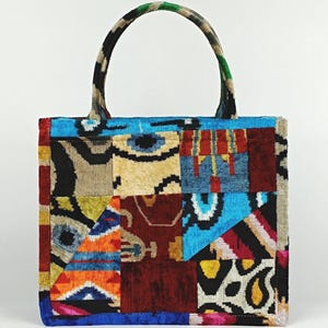 Puede incluir: Un bolso tote de patchwork con un dise&ntilde;o colorido que presenta patrones geom&eacute;tricos y formas abstractas en tonos de azul, rojo, naranja, amarillo, negro y blanco.