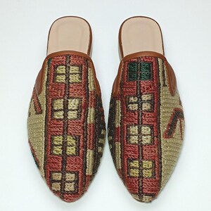 May include: A pair of brown leather and fabric slippers with a pointed toe and a geometric pattern in shades of red, green, and beige.