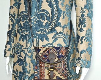 May include: A small brown leather crossbody bag with a colorful patterned flap. The bag has a buckle closure and a long adjustable strap.