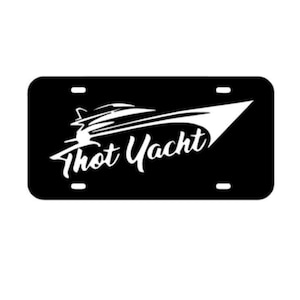 May include: Black and white license plate with a white silhouette of a yacht and the text "Thot Yacht".