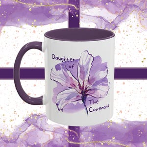 May include: White ceramic mug with a purple rim and handle. The mug features a watercolor illustration of a purple flower with the text "Daughter of The Covenant".