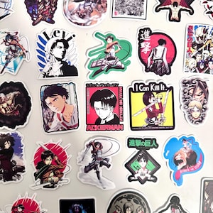 Puede incluir: Una colección de pegatinas con temática de anime que presentan personajes e imágenes de la serie Attack on Titan. Las pegatinas muestran varios personajes en poses de acción, con texto como "ACKERMAN" y "I Can Kill It."