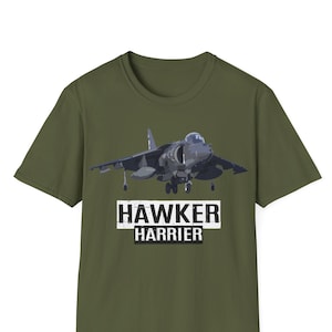May include: A green t-shirt with a graphic of a Hawker Harrier jet plane. The text "Hawker Harrier" is printed in white on a black rectangle below the plane.