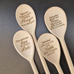 Könnte beinhalten: Vier helle Holzlöffel mit eingravierten deutschen Texten. Die Löffel tragen die Aufschriften: 'Männer haben auch Gefühle. Hunger zum Beispiel.', 'Ich koche gerne mit Wein.', 'Die geheime Zutat ist immer Liebe!' und 'Manchmal sollte man sich lieber Nudeln statt Sorgen machen!'