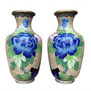 Pode incluir: Um par de vasos cloisonné a condizer com um fundo creme e um padrão geométrico de fio de ouro fino. Cada vaso apresenta grandes peónias azuis vibrantes com folhas verdes e pequenos detalhes florais cor-de-rosa, rematados com um rebordo dourado.