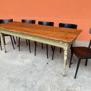 Könnte beinhalten: Ein Esstisch aus Holz mit hellgrüner Basis und natürlicher Holzplatte. Der Tisch ist von vier schwarzen Stühlen umgeben. Die Tischabmessungen betragen ca. 183 cm Länge und 91 cm Breite.