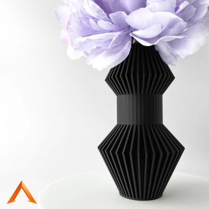 Könnte beinhalten: Eine schwarze geometrische Vase mit plissiertem Design, die einen Strauß helllila Blumen hält.