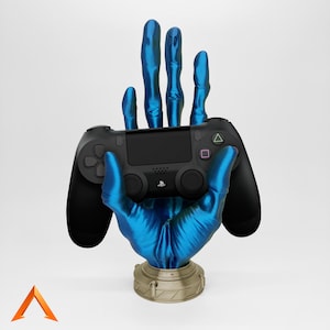 Könnte beinhalten: Eine blaue Handskulptur, die einen schwarzen PlayStation 4-Controller hält. Die Hand ist aus einem glatten, glänzenden Material gefertigt und hat eine metallische Basis.