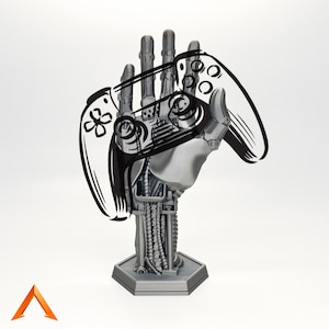 Op de afbeelding: Een grijze, robot-achtige hand die een zwart-witte illustratie van een videogamecontroller vasthoudt. De hand is bevestigd aan een grijze basis.