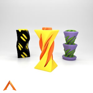Puede incluir: Tres objetos impresos en 3D, cada uno con un diseño único. El primero es un cilindro negro y amarillo con un patrón de espiral. El segundo es un cilindro amarillo y naranja con un diseño en espiral. El tercero es un cilindro morado y verde con un diseño apilado.