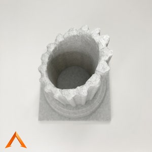 May include: A white ceramic planter shaped like a column with a fluted top. The planter has a square base.