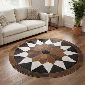 Peut inclure: Tapis rond avec un motif géométrique en forme d'étoile. Le tapis présente un cercle noir central entouré de formes alternées blanches, noires et de différentes nuances de marron. Il est posé sur un parquet, près d'un canapé beige.