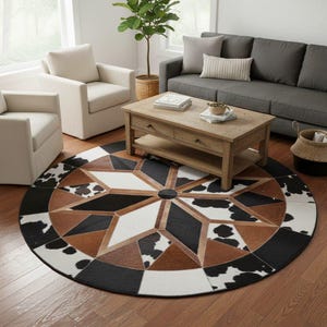May include: A round area rug with a geometric starburst design. The rug features a black, white, and brown color palette with cowhide accents. The rug is placed in a living room setting with a sofa, chairs, and a coffee table.
