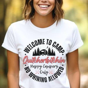 May include: White t-shirt with a graphic that reads "WELCOME TO CAMP Quitchebitchin Happy Campers Only NO WHINING ALLOWED". The design includes a camper, trees, and crossed arrows in a circular layout.