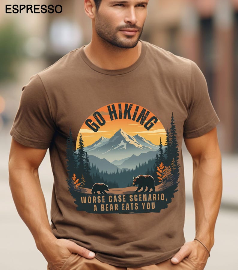 May include: A brown t-shirt with a graphic of a mountain range and the text "Go Hiking" in a circle. The graphic also includes two bears and the text "Worse case scenario, a bear eats you".