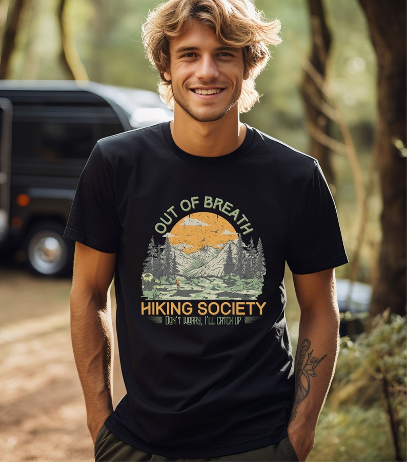 May include: A black t-shirt with a vintage-style graphic of a mountain landscape and the text "Out of Breath Hiking Society Don't worry, I'll catch up".