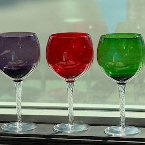 Puede incluir: Una taza de cerámica blanca con un asa negra y el texto "But First, Coffee" en negro, con una fuente de estilo manuscrito. La taza está sobre una superficie blanca.