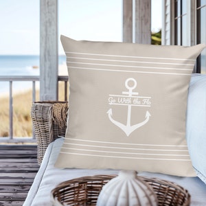 May include: Beige throw pillow with white horizontal stripes and a white anchor with the text "Go With the Flo" on a banner above the anchor.
