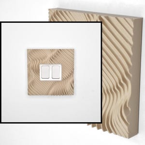 May include: A light beige square light switch cover plate featuring a textured, wavy, three-dimensional pattern. The cover plate has a central rectangular cutout containing two white rectangular rocker switches, set against a plain white background.