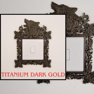 May include: A decorative light switch cover in titanium dark gold. The cover features a detailed wolf head at the top and ornate floral and scrollwork around the switch. The text "TITANIUM DARK GOLD" is displayed in red.