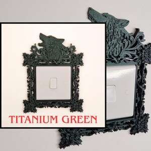 May include: Titanium green decorative light switch cover with a wolf head design. The cover has an ornate, floral-inspired frame. The text "TITANIUM GREEN" is displayed in red at the bottom of the image.