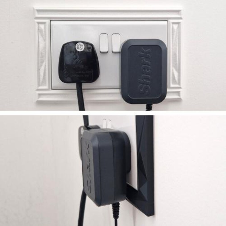 May include: A black Shark brand power adapter plugged into a white wall outlet alongside a black three-prong plug. The adapter features a rectangular shape with rounded corners and the word Shark embossed vertically on its front surface.
