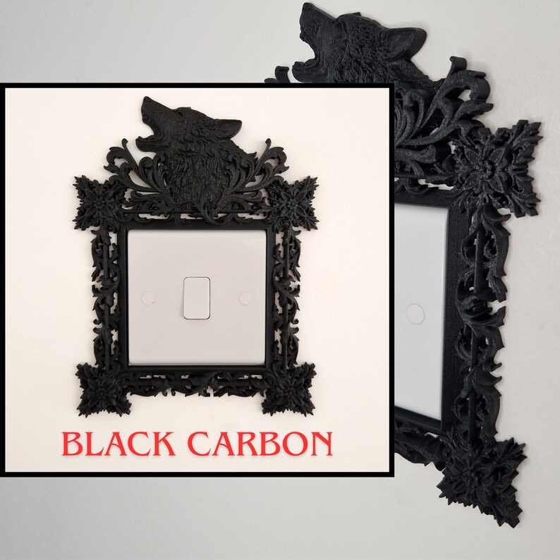 May include: Black carbon fiber light switch cover with a decorative frame. The frame features a howling wolf at the top and ornate floral and scrollwork designs. The text "BLACK CARBON" is displayed in red at the bottom.