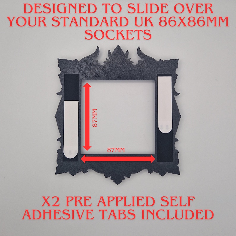 May include: A black decorative frame with ornate edges, designed to fit over UK 86x86mm sockets. The frame measures 87mm by 87mm internally and includes two pre-applied self-adhesive tabs. Text on the frame reads "DESIGNED TO SLIDE OVER YOUR STANDARD UK SOCKETS".