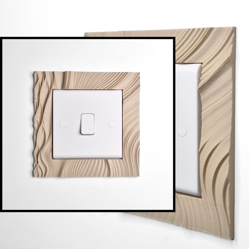 May include: A square light switch cover plate featuring a beige, textured frame with flowing, wave-like patterns surrounding a central white rectangular switch. The design includes a smooth white center toggle and two circular screw covers on the sides.