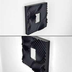 May include: A black light switch cover plate featuring a three-dimensional, wavy, rippled texture across its entire surface. The square-shaped cover has a central rectangular cutout that frames a standard white rocker-style light switch toggle.