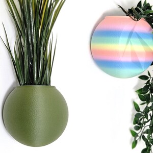 May include: Two round wall planters, one green and one with rainbow stripes. The planters are made of ceramic and have a smooth, matte finish.