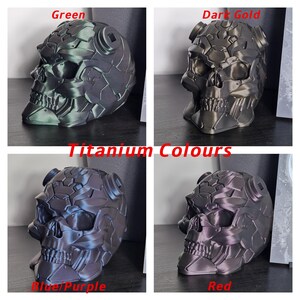 May include: Four 3D printed skulls in different metallic colours: green, dark gold, blue/purple, and red. The skulls are detailed and have a textured surface. The image is titled "Titanium Colours".