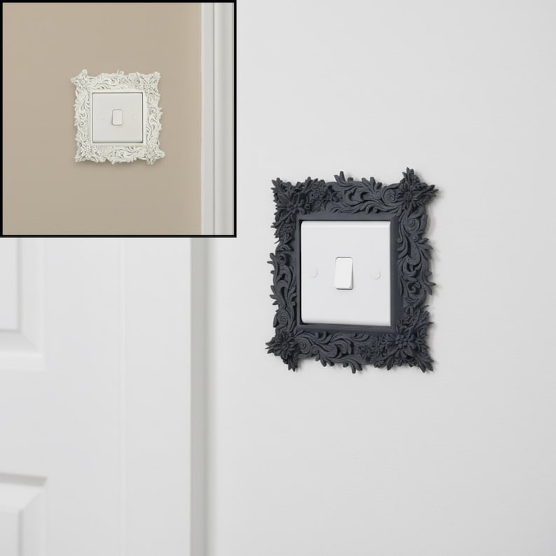 May include: Decorative light switch cover with an ornate floral design. The cover is square and surrounds a white light switch. The frame is a dark gray color, adding a touch of elegance to the wall.
