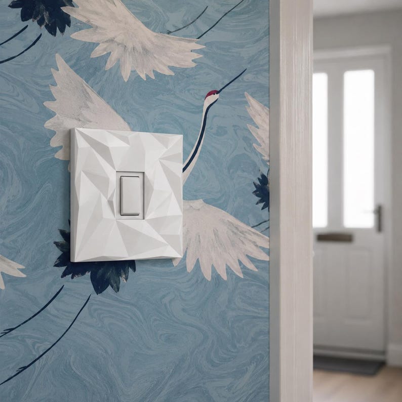 White geometric light switch cover installed in a modern hallway.