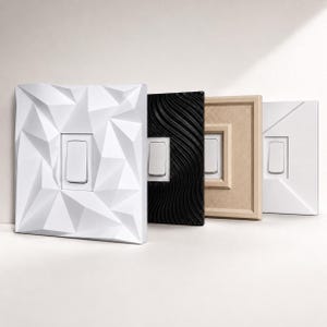 May include: A collection of four rectangular light switch covers arranged in a row. The first is white with a geometric faceted surface, the second is black with a wavy texture, the third is beige with a stepped frame, and the fourth is white.