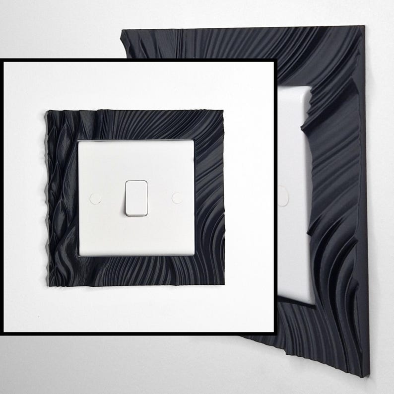 May include: A white light switch featuring a decorative black frame with a textured, wavy, and rippled surface pattern. The frame surrounds the square switch plate, which includes a central toggle and two circular screw covers on the sides.