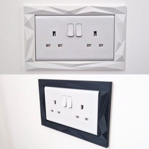 Może przedstawiać: Dwa podw&oacute;jne gniazdka elektryczne ścienne z białą prostokątną płytką czołową, dwoma przełącznikami i portami z trzema otworami. Jedno gniazdko otoczone jest białą geometryczną ramką, a drugie umieszczone w ciemnoszarej geometrycznej ramce.