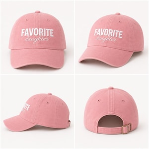K&ouml;nnte beinhalten: Staubrosa Baseballkappe mit dem wei&szlig;en Schriftzug "FAVORITE daughter". Die Kappe hat einen gebogenen Schirm, einen Metallverschluss und eine runde Oberseite.