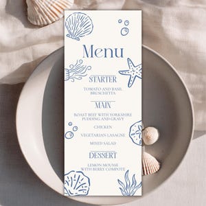 May include: A vertical rectangular menu card with a cream background and blue ink illustrations of seashells, a starfish, and bubbles. The text reads Menu, Starter, Tomato and Basil Bruschetta, Main, Roast Beef with Yorkshire Pudding and Gravy, Chicken, Vegetarian Lasagne, Mixed Salad, Dessert, Lemon Mousse with Berry Compote.