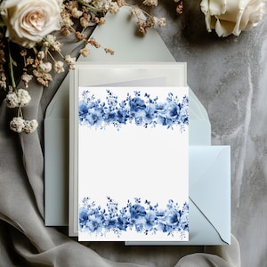 Könnte beinhalten: Eine weiße Karte mit einem blauen Blumenrand. Die Blumen sind im Aquarell-Stil gehalten und in einer Reihe am oberen und unteren Rand der Karte angeordnet. Die Karte liegt auf einem hellblauen Umschlag.