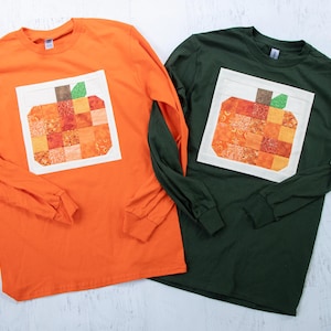 May include: Two long-sleeved t-shirts with a patchwork pumpkin design. One shirt is orange and the other is green.