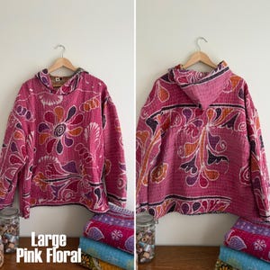 May include: A large pink floral hoodie with a hood, displayed on a wooden hanger. The hoodie features a vibrant floral pattern in shades of pink, orange, and purple. The text "Large Pink Floral" is visible at the bottom.