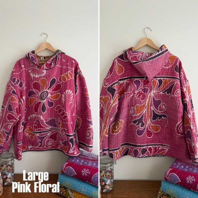 May include: A large pink floral hoodie with a hood, displayed on a wooden hanger. The hoodie features a vibrant floral pattern in shades of pink, orange, and purple. The text "Large Pink Floral" is visible at the bottom.