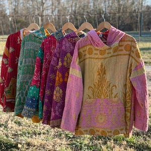 May include: A white ceramic mug with a black handle and the text "But First, Coffee" in a black, bold font. The mug is sitting on a wooden surface. The mug is approximately 4 inches tall.